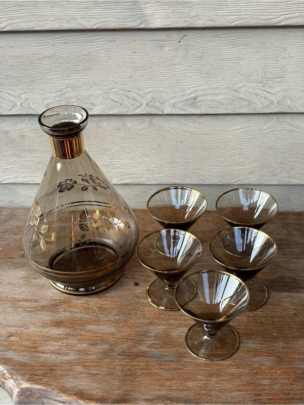Art Deco decanter set features smoky purple glass adorned with a gold floral
